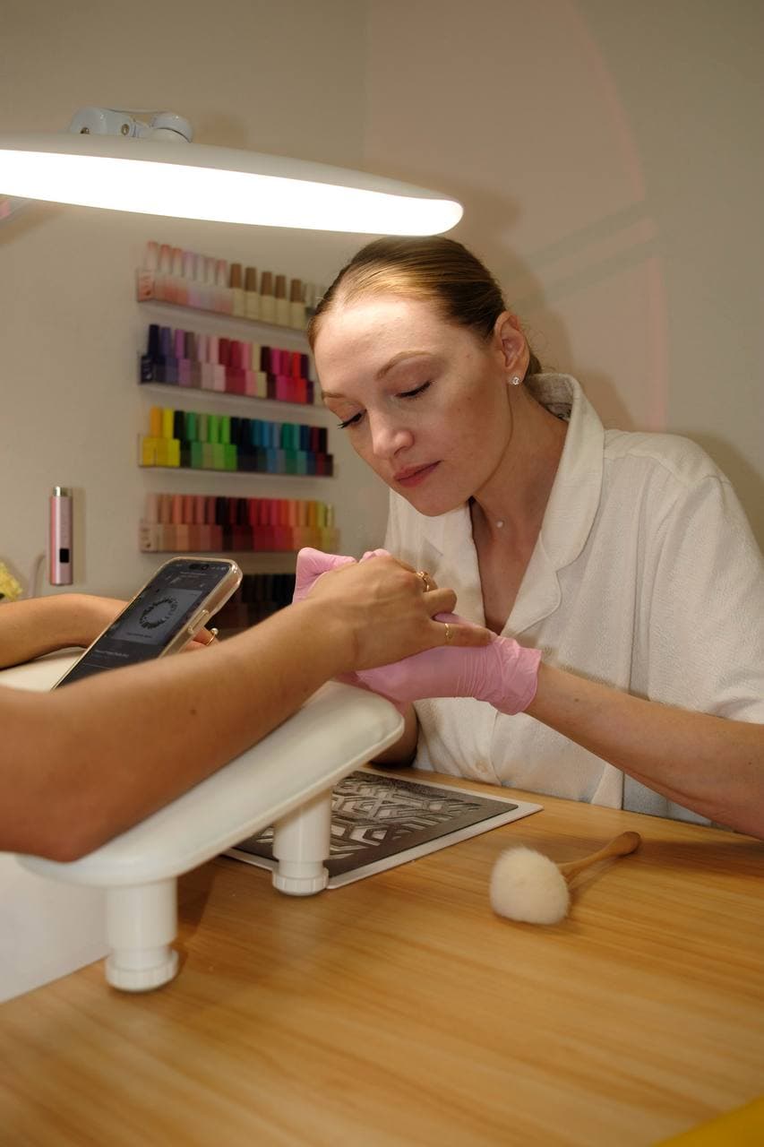 Polina working at nail station — attentive to client