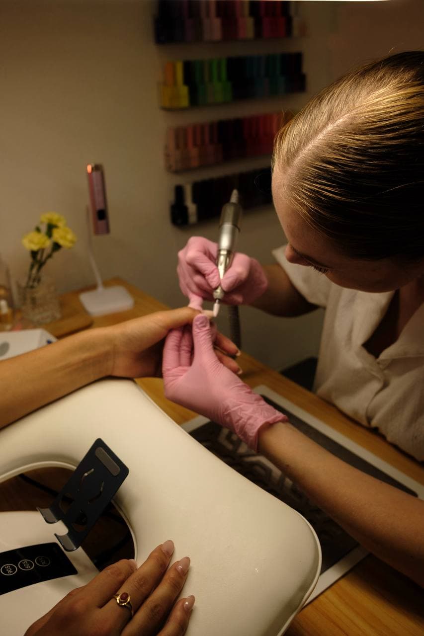 Nail technician working with drill — focused detail work