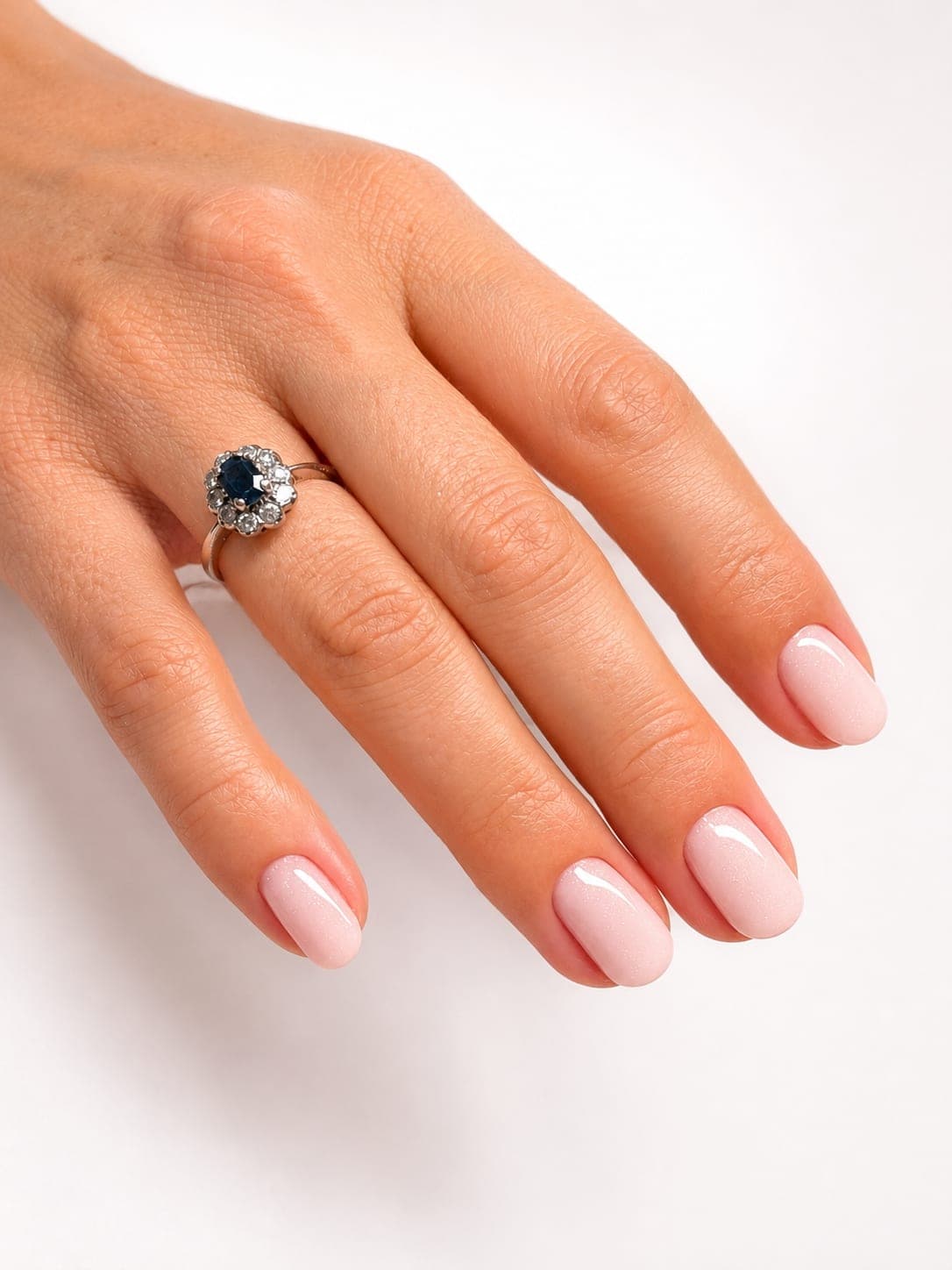Milky pink manicure with a sapphire ring