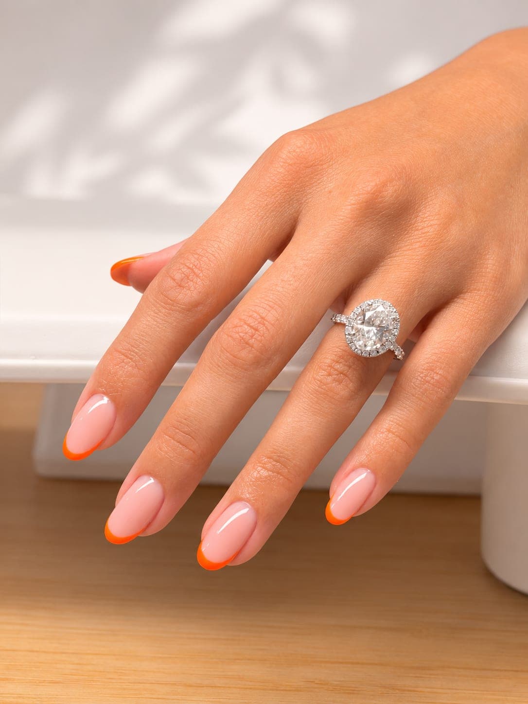 Orange-tip French manicure on almond nails with a diamond ring